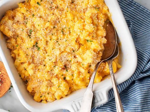 Baked macaroni and cheese in a white ceramic dish with a serving spoon